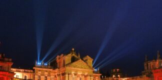 Blenheim Palace façade glowing amber with search‑lights and Christmas trees