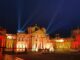Christmas At Blenheim Palace Blenheim Palace façade glowing amber with search‑lights and Christmas trees